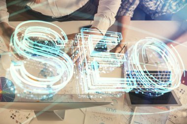 SEO hologram çizimleri ve birlikte çalışan kadın ve erkeğin çifte pozu. Arama motoru konsepti. Bilgisayar arkaplanı. Üst Görünüm.