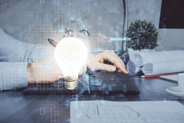 Dijital bir cihaz ve ampul hologram çizimi kullanarak insanın ellerini tutarken çift pozlama. Fikir kavramı.