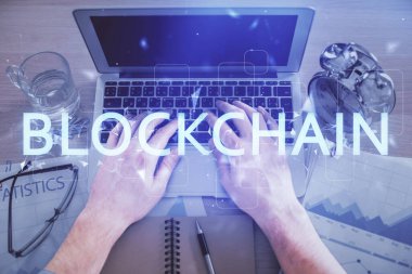 Bilgisayar klavyesinin ve şifreli para birimi temalı hologram çiziminin üzerine iki kez yazılan el pozu. Üst Manzara. Engelleme zinciri kavramı.