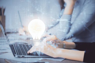 Bilgisayarda yazı yazan ve ampul çizen bir kadının ellerine iki kez maruz kalmış. Fikir kavramı.