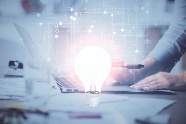 Bilgisayarda yazı yazan ve ampul çizen bir kadının ellerine iki kez maruz kalmış. Fikir kavramı.