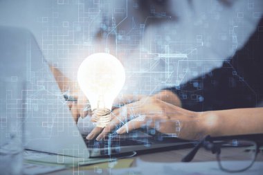 Bilgisayarda yazı yazan ve ampul çizen bir kadının ellerine iki kez maruz kalmış. Fikir kavramı.