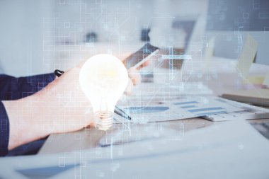 Dijital bir cihaz ve ampul hologram çizimi kullanarak insanın ellerini tutarken çift pozlama. Fikir kavramı.