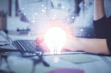 Bilgisayarda yazı yazan ve ampul çizen bir kadının ellerine iki kez maruz kalmış. Fikir kavramı.