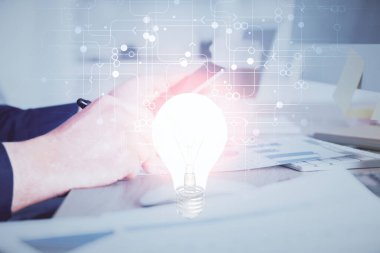 Dijital bir cihaz ve ampul hologram çizimi kullanarak insanın ellerini tutarken çift pozlama. Fikir kavramı.