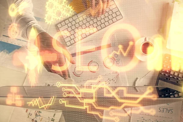 Bilgisayar klavyesinin ve SEO hologram çiziminin üzerine yazı yazan bir adamın eline çok kez maruz kalmış. Üst Manzara. Arama optimizasyon kavramı.