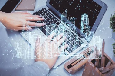 Bilgisayarda yazı yazan kadın elleri ve çizim yapan binalar. Akıllı şehir konsepti.