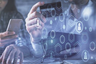 Bir kredi kartı ve sosyal ağ temalı hologram çizimi tutan bir kadın ve erkeğin online alışverişine iki kez maruz kalıyorlar. Bağlayan ve E-ticaret yapan insanlar çevrimiçi konsept üzerinden ödeme yapıyorlar.