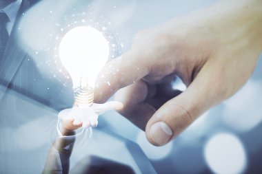 Dijital bir cihaz ve ampul hologram çizimi kullanarak insanın ellerini tutarken çift pozlama. Fikir kavramı.