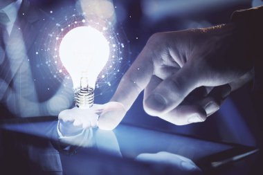 Dijital bir cihaz ve ampul hologram çizimi kullanarak insanın ellerini tutarken çift pozlama. Fikir kavramı.