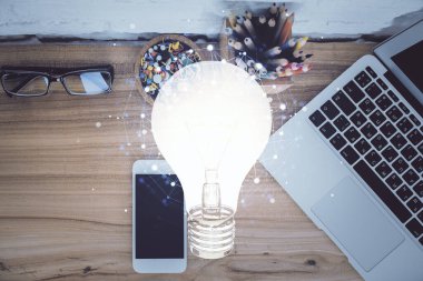 Ampulü telefonla masanın üzerine çizerken çift pozlama. Üst Manzara. Fikir kavramı.
