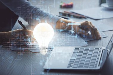 Bilgisayarda yazı yazan ve ampul çizen bir kadının ellerine iki kez maruz kalmış. Fikir kavramı.