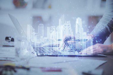 Bilgisayarda yazı yazan kadın elleri ve çizim yapan binalar. Akıllı şehir konsepti.