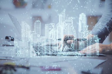 Bilgisayarda yazı yazan kadın elleri ve çizim yapan binalar. Akıllı şehir konsepti.