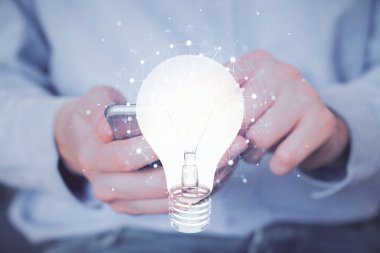 Dijital bir cihaz ve ampul hologram çizimi kullanarak insanın ellerini tutarken çift pozlama. Fikir kavramı.