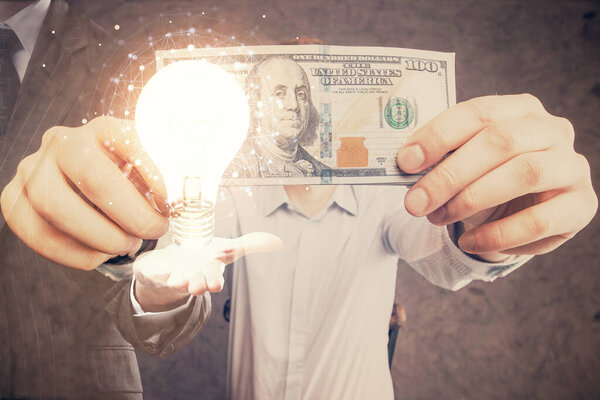 Multi exposure of bulb drawing hologram and USA dollars bills and man hands. Business Idea concept.