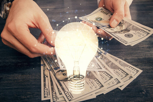 Multi exposure of bulb drawing hologram and USA dollars bills and man hands. Business Idea concept.