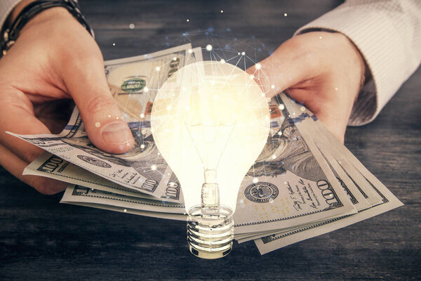 Multi exposure of bulb drawing hologram and USA dollars bills and man hands. Business Idea concept.
