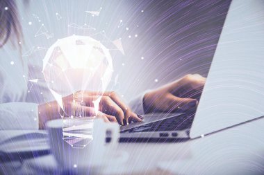 Bilgisayarda yazı yazan ve ampul çizen bir kadının ellerine iki kez maruz kalmış. Fikir kavramı.