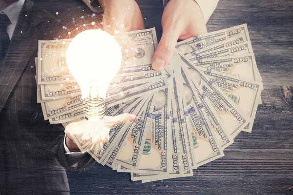 Multi exposure of bulb drawing hologram and USA dollars bills and man hands. Business Idea concept.