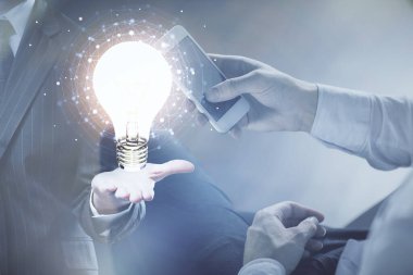 Dijital bir cihaz ve ampul hologram çizimi kullanarak insanın ellerini tutarken çift pozlama. Fikir kavramı.