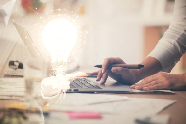 Bilgisayarda yazı yazan ve ampul çizen bir kadının ellerine iki kez maruz kalmış. Fikir kavramı.