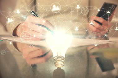 Ampul hologramına çift pozlama ve mobil cihaz kullanan bir kadın. Fikir kavramı.