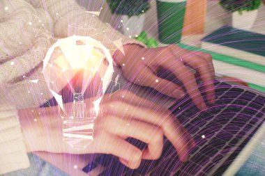 Bilgisayarda yazı yazan ve ampul çizen bir kadının ellerine iki kez maruz kalmış. Fikir kavramı.