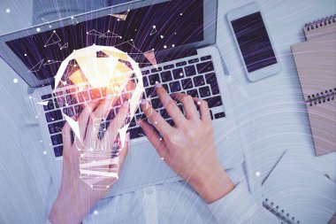 Bilgisayar ve ampul hologramı çizimleri üzerinde çalışan kadın elleri çift pozlama. Üst Manzara. Fikir kavramı.