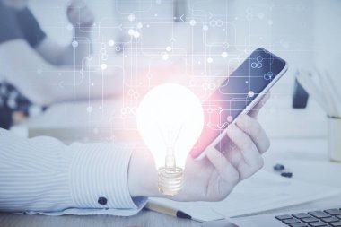 Dijital bir cihaz ve ampul hologram çizimi kullanarak insanın ellerini tutarken çift pozlama. Fikir kavramı.