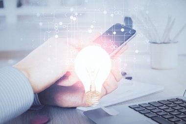 Dijital bir cihaz ve ampul hologram çizimi kullanarak insanın ellerini tutarken çift pozlama. Fikir kavramı.