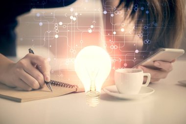 Ampul hologramına çift pozlama ve mobil cihaz kullanan bir kadın. Fikir kavramı.