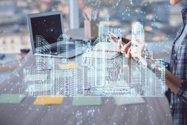 Bilgisayarda yazı yazan kadın elleri ve çizim yapan binalar. Akıllı şehir konsepti.