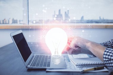 Dijital bir cihaz ve ampul hologram çizimi kullanarak insanın ellerini tutarken çift pozlama. Fikir kavramı.