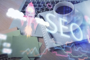 SEO yazılarını ve masaüstünü kahve ve masa arkasında eşyalar eşliğinde iki kez görüntüle. Arama optimizasyonu kavramı.