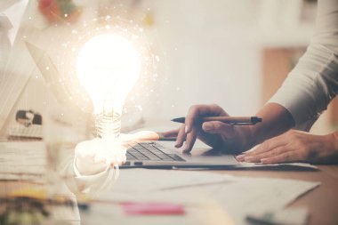 Bilgisayarda yazı yazan ve ampul çizen bir kadının ellerine iki kez maruz kalmış. Fikir kavramı.