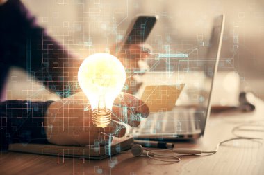 Dijital bir cihaz ve ampul hologram çizimi kullanarak insanın ellerini tutarken çift pozlama. Fikir kavramı.