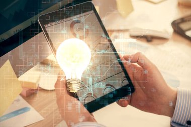 Dijital bir cihaz ve ampul hologram çizimi kullanarak insanın ellerini tutarken çift pozlama. Fikir kavramı.