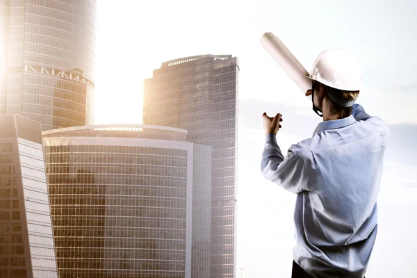 Builder pointing at skyscraper — Stock Photo, Image