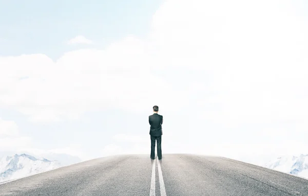 Uomo d'affari in piedi e guardando sulla strada — Foto Stock