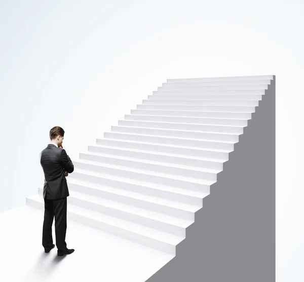 Думающий бизнесмен, стоящий у лестницы — стоковое фото