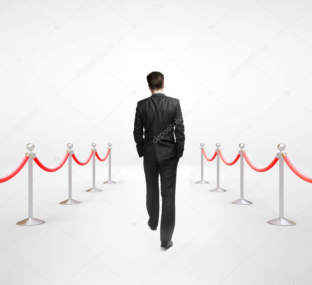 businessman walking and stanchions barrier in white room