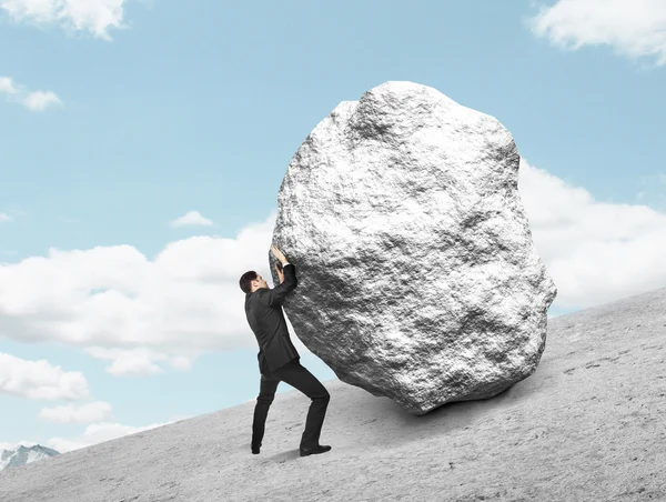 Hombre de negocios empujando piedra — Foto de Stock