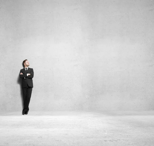 Jovem homem de negócios em pé na sala de concreto — Fotografia de Stock