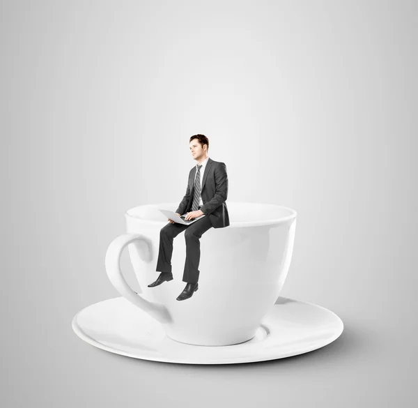 Businessman sitting on coffee cup — Stock Photo, Image
