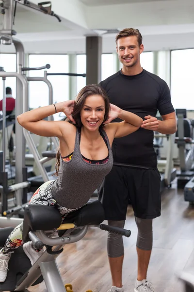 Vrouw met personal trainer in de sportschool — Stockfoto