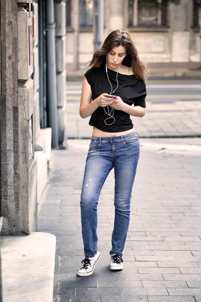 Woman listens music and walks on the street — Stock Photo, Image