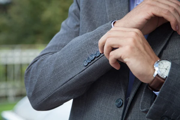 Elegante jonge zakenman in smoking dichtknopen de jas — Stockfoto