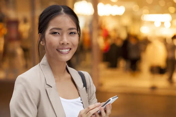 Jonge vrouw en slimme telefoon lopen op straat — Stockfoto