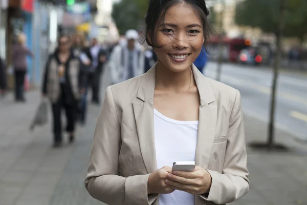 Jonge vrouw en slimme telefoon lopen op straat — Stockfoto